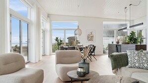 Tilava olohuone, jossa on suuret ikkunat, ruokailutila ja keittiö.
