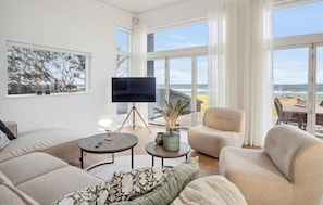 Relax in this stylish living area with a large flat-screen TV, two sofas, and a chair, offering a view of the ocean.