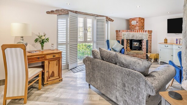 A living room with a fireplace, a dining area with a table and chairs, and a sofa. - Discover Yorkshire’s charms from this cosy holiday let. (Warmfield, near Wakefield)