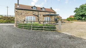 A stone building with a tiled roof, a covered patio, and a gravel driveway. - Discover Yorkshire’s charms from this cosy holiday let. (Warmfield, near Wakefield)