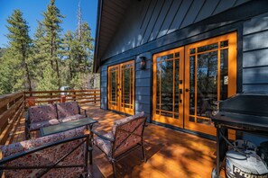 A wooden deck with outdoor furniture, large windows, and a grill. - Forest Escape  (Fawnskin)