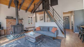 Una sala de estar moderna con chimenea, una escalera y un comedor.