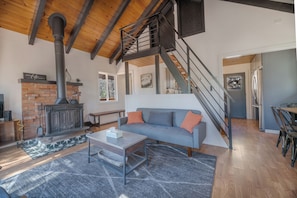 Una sala de estar moderna con chimenea, una escalera y un comedor.