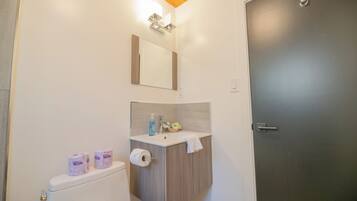 Un baño con inodoro, lavamanos, espejo y toallero.