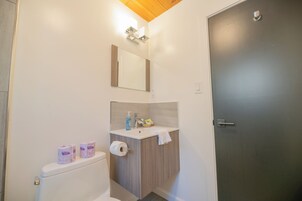 Un baño con inodoro, lavamanos, espejo y toallero.