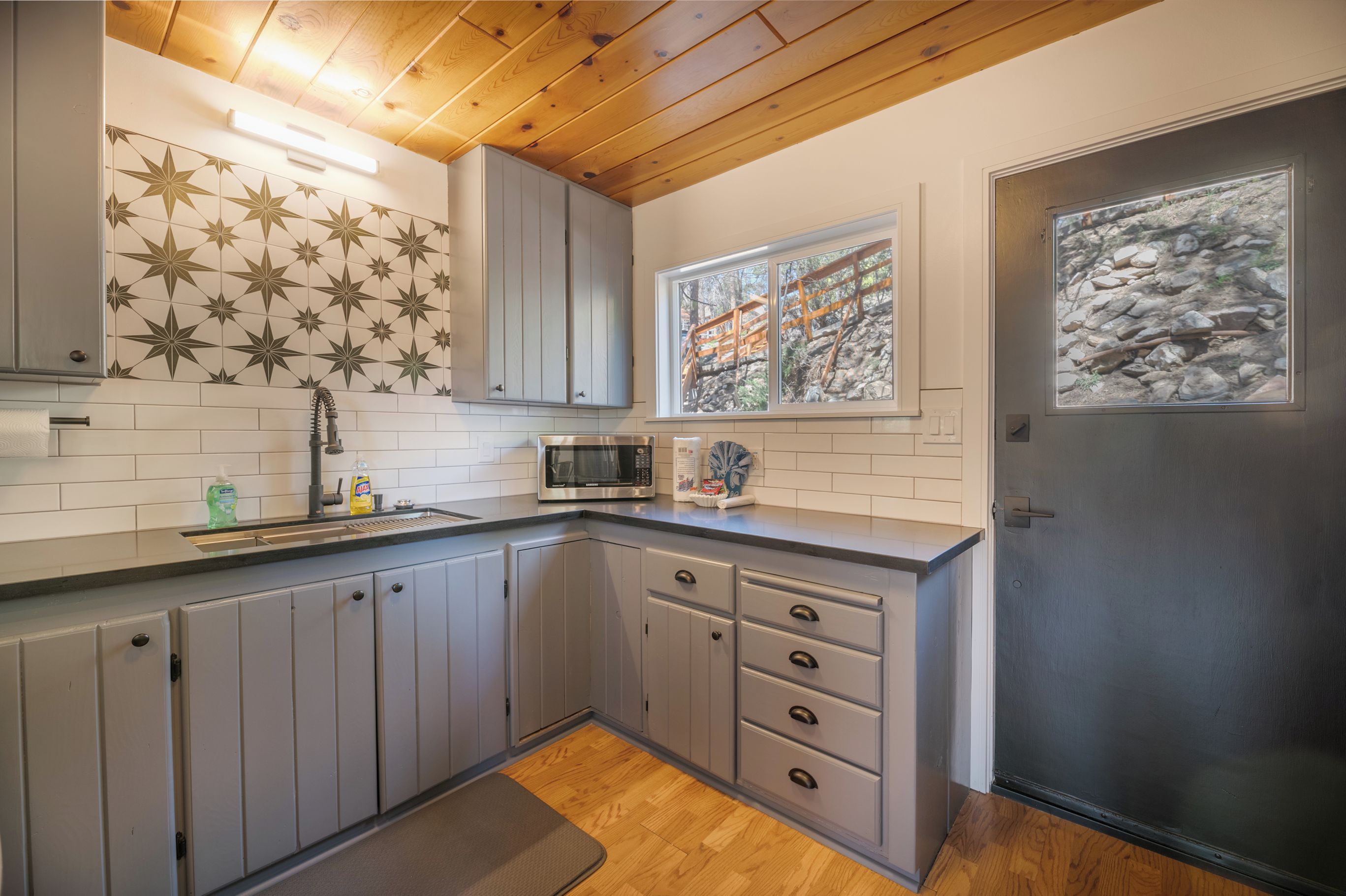 A kitchen with grey cabinets, a microwave, and a sink.