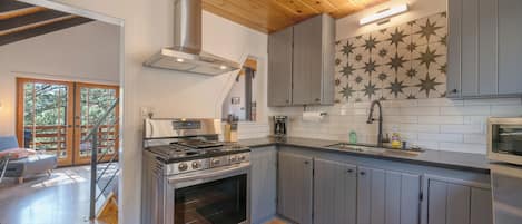 A modern kitchen with a large stove, grey cabinets, and a star-patterned backsplash.