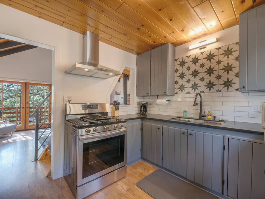 A modern kitchen with a large stove, grey cabinets, and a star-patterned backsplash.