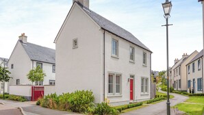 Une rue résidentielle bordée de maisons, avec une porte rouge et un lampadaire.