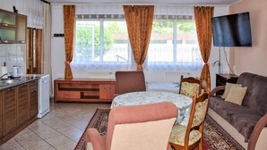 A compact living space with a kitchenette, a dining area with a table and chairs, a sofa, and a TV mounted on the wall. - Awesome apartment in Ustka with WiFi (Ustka)