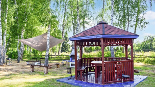 A wooden gazebo with a blue roof and a picnic table in a grassy area with trees. - Awesome apartment in Ustka with WiFi (Ustka)