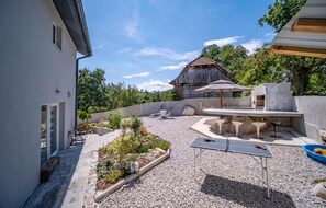 A patio area with a ping pong table, outdoor seating, and a barbecue setup. - Lovely home in Sculac with sauna (Sculac)