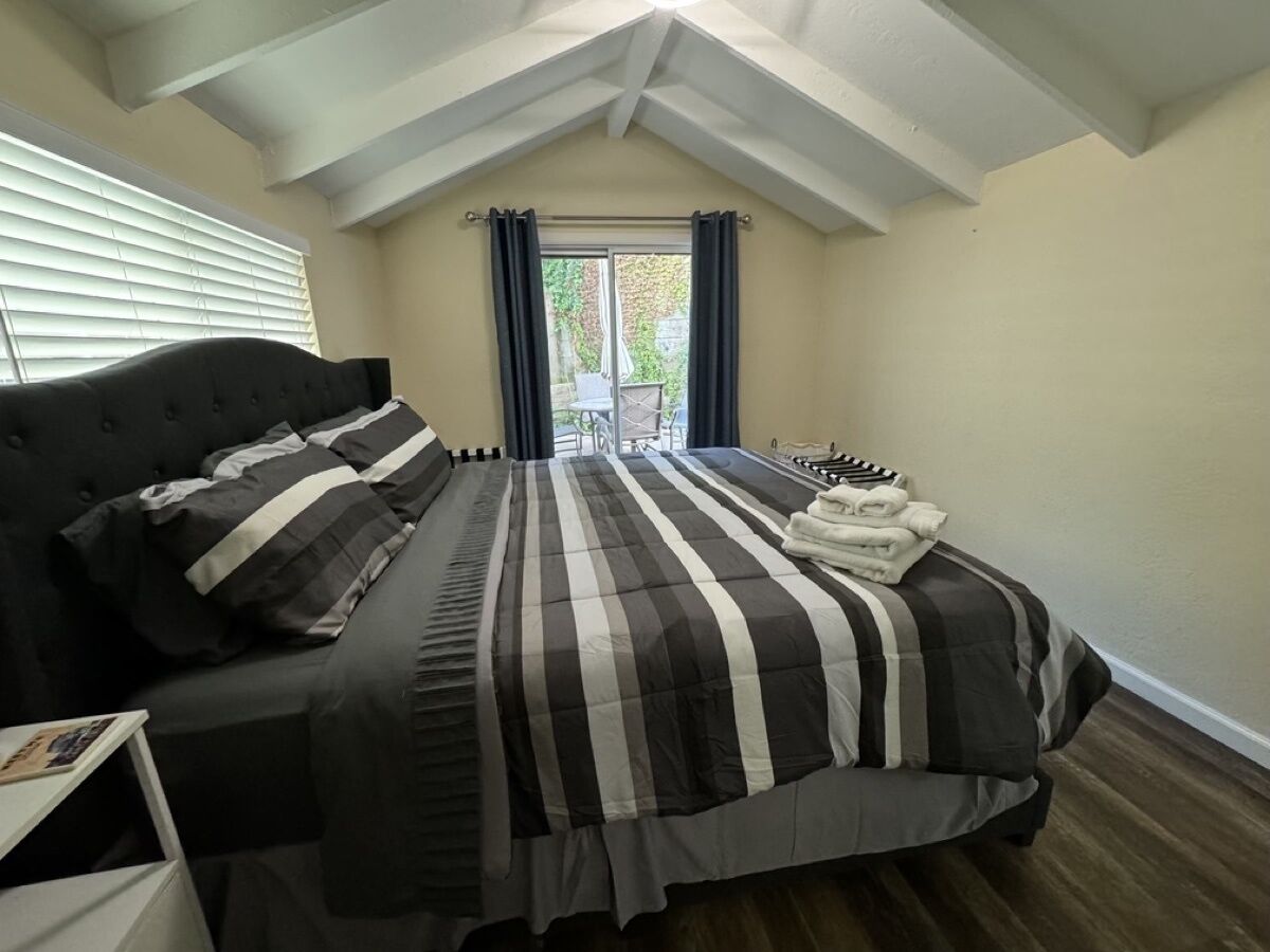 A bedroom with a bed, a nightstand, and a window with curtains.