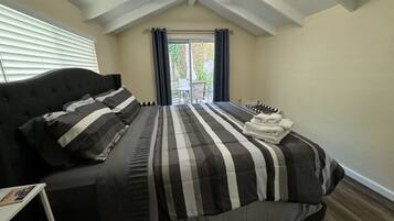 A bedroom with a bed, a nightstand, and a window with curtains.