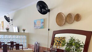 A dining area with a wooden table, chairs, and a colorful woven tablecloth. There are potted plants on the table and a mirror on the wall. - BOM SOSSEGO POUSADA (Delmiro Gouveia)