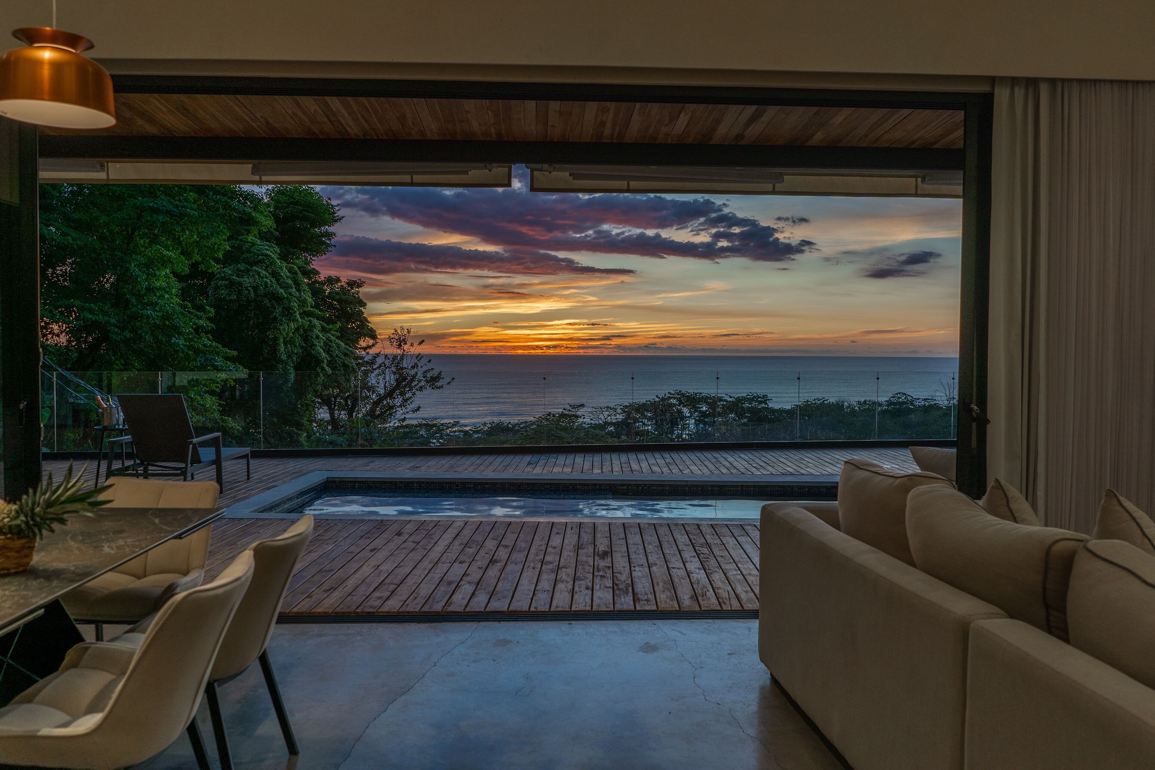 Una sala de estar moderna con un amplio ventanal que ofrece vistas a un atardecer.