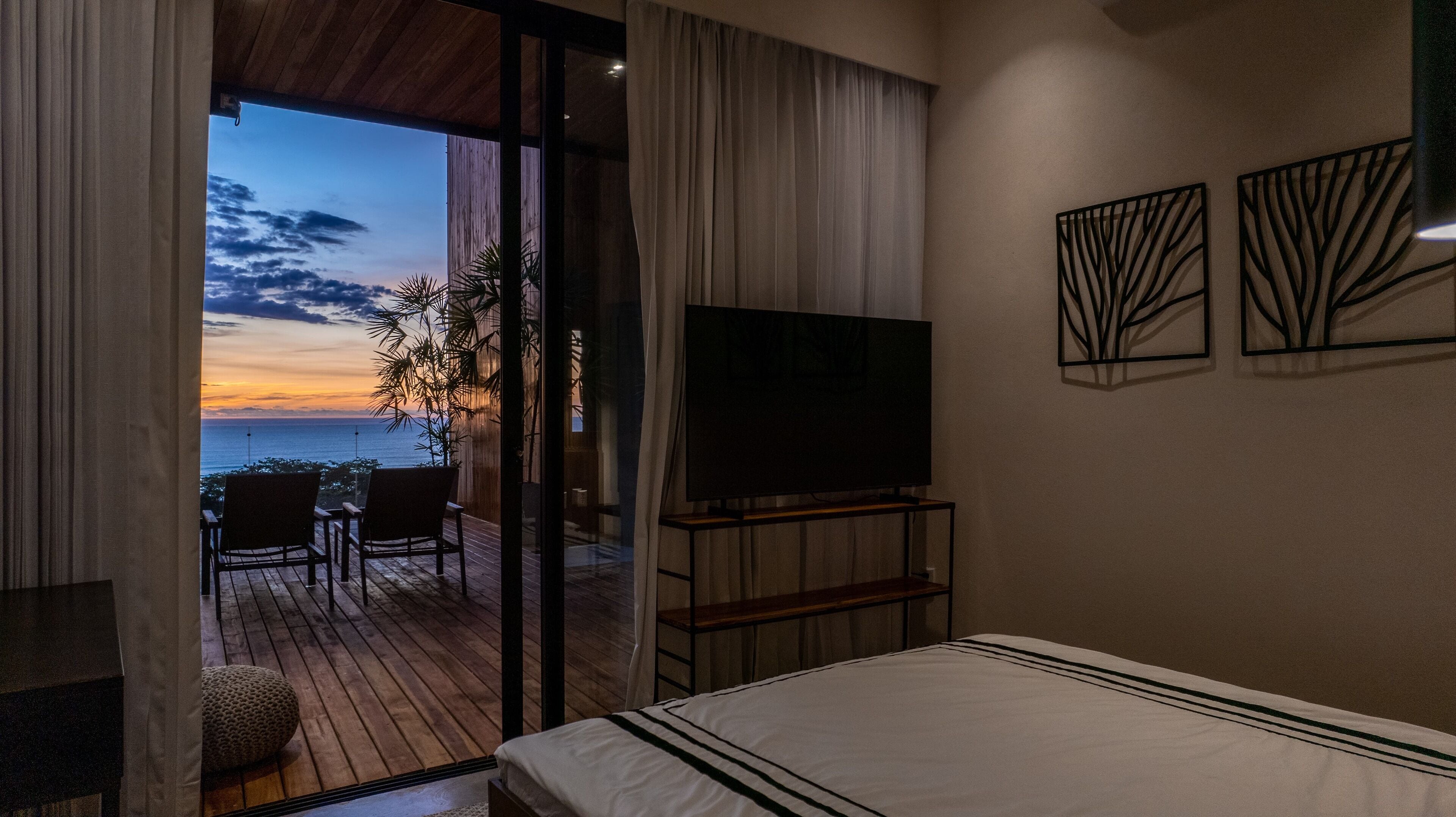 Une chambre d’hôtel avec un balcon, un lit, une télévision et deux œuvres d’art murales.