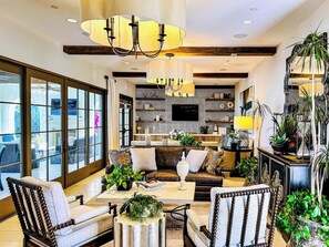 A spacious living room with a large sofa, armchairs, a coffee table, and a television.
