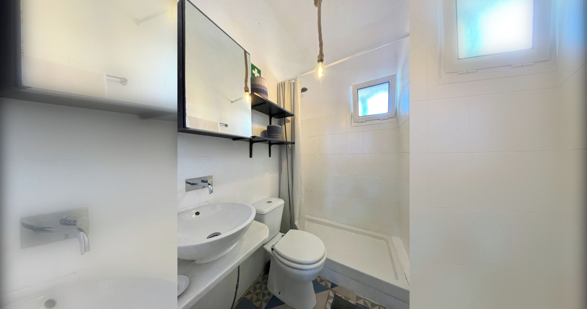 A bathroom with a white sink, toilet, and shower area. There is a mirror above the sink and a small window above the shower.