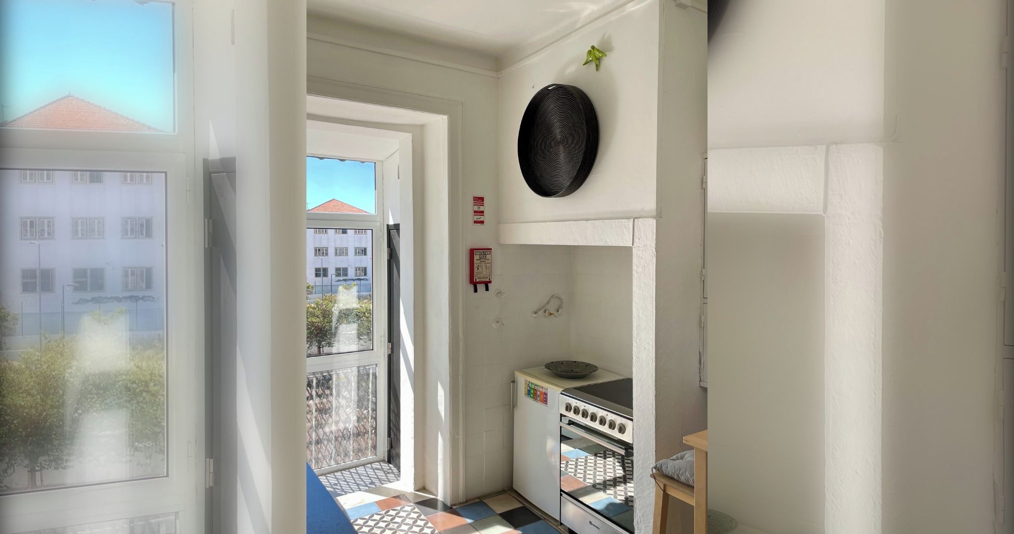 Uma cozinha pequena com fogão, pia e janela com vista para um edifício.