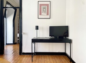 A room with a black desk, a television, and a framed picture on the wall. - Central Hidden Gem Rustic Modern 2BDR City Flat (Lisboa)