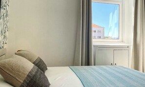 Ein Hotelzimmer mit Bett, Fenster und Blick auf Gebäude sowie einer Heizung.