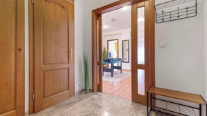 A hallway with wooden doors, a tiled floor, and a bench with a wire shelf. - Exclusive Apartment in Centre (Bratislava)