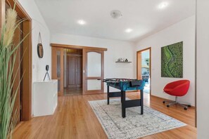 A room with a foosball table, a red office chair, and a wooden floor. - Exclusive Apartment in Centre (Bratislava)