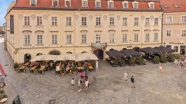 A historic building with a courtyard, outdoor seating, and a sign for 'Vinimka'. - Exclusive Apartment in Centre (Bratislava)
