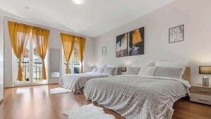 A modern bedroom with two beds, a large window with yellow curtains, and artwork on the walls. - Exclusive Apartment in Centre (Bratislava)