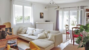 Una sala de estar con un sofá, un sillón amarillo, una mesa con un plato y un radiador.