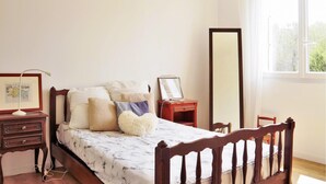 Un dormitorio ordenado con una cama, una mesita de noche, un espejo y un aparador.