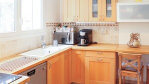 Una cocina con armarios de madera, microondas, cafetera y lavamanos.