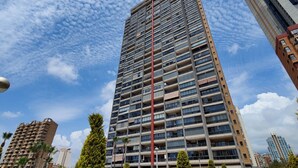 A high-rise building with multiple balconies, surrounded by other buildings and greenery. - DOS CALAS sunny apartment (Benidorm)