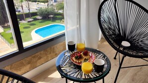 A balcony with a glass table set with breakfast items, a view of a swimming pool, and a cityscape. - DOS CALAS sunny apartment (Benidorm)