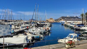 A marina with numerous boats docked, a signboard, and a mountainous backdrop.