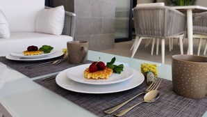 Une table à manger dressée avec des assiettes, un dessert, une tasse et des couverts.