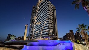 Un immeuble de grande hauteur doté de balcons et d’une enseigne lumineuse sur laquelle on peut lire « SUNSET CLIFTS ».