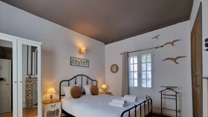 A bedroom with a bed, bedside tables, a hanging light fixture, a window with curtains, and a door leading to another room. - La Terrasse de Sacha | House with Terrace & Fireplace | 4 Guests (Honfleur)