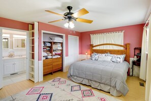 Une chambre à coucher comprenant un lit, un ventilateur de plafond, une armoire et une commode.