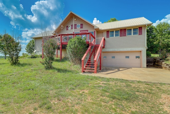 Une maison à deux étages avec un escalier rouge, un garage et une pelouse bien entretenue.