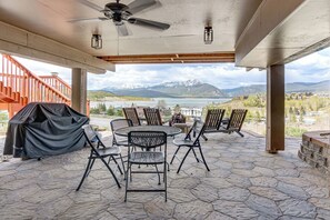 Eine überdachte Terrasse mit Sitzgelegenheiten im Freien, einem Deckenventilator und Blick auf Berge und einen See.