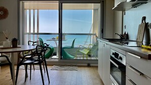 Eine moderne Küche mit Meerblick, ein Essbereich mit Stühlen und ein Tisch mit Pflanze und Vase.