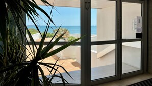 Ein Zimmer mit einer Schiebeglastür, die auf einen Balkon mit Meerblick führt.