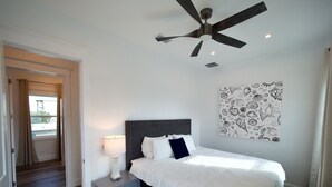 A bedroom with a bed, a nightstand, a ceiling fan, a wall with a seashell pattern, and a view through a door. - 6 BR Townhome Oceanvws Rooftop Deck Pool (Panama City Beach)