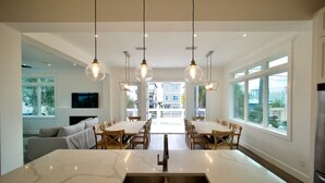 A modern kitchen with a large island, pendant lights, and a view of the outside. - 6 BR Townhome Oceanvws Rooftop Deck Pool (Panama City Beach)