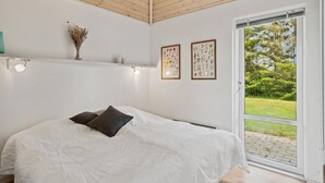 Una camera da letto con un letto, una finestra e due quadri floreali appesi al muro.
