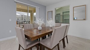 A dining room with a wooden table, beige chairs, and white vases. - 6BR Villa with Pool & Games Room, Near Disney (Davenport)