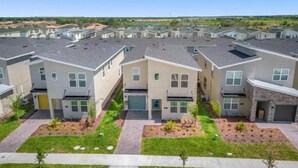 A row of modern townhouses with a central courtyard, each with a garage and a small front yard. - 6BR Villa with Pool & Games Room, Near Disney (Davenport)