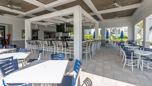 An outdoor patio area with tables and chairs, a bar, and a kitchen in the background. - 6BR Villa with Pool & Games Room, Near Disney (Davenport)